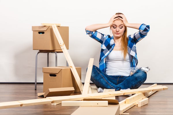 Une femme essaie de monter un meuble mais n'y arrive pas