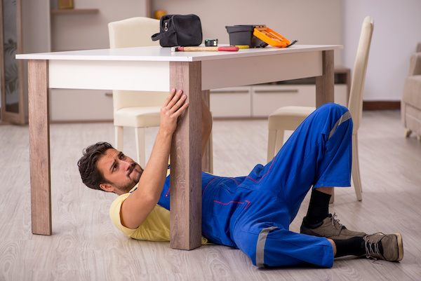 Un monteur de meuble sous une table IKEA