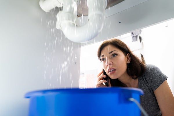 Une femme au téléphone pendant que son évier fuit