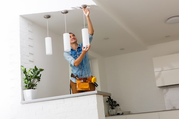 Un électricien en train de fixer un luminaire au plafond