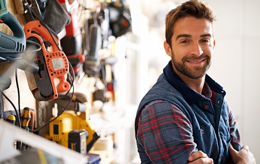 Un Homme a tout faire devant un mur d'outils